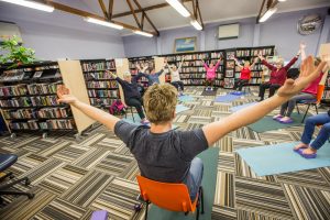 Internal view of library with people doing yoga stretches in chair