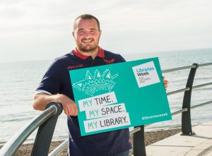 Man carrying Libraries Week promotional poster