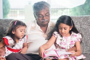 Two children reading books with an adult