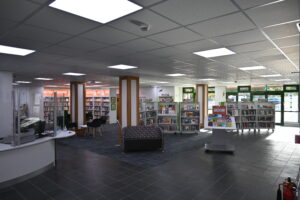 General view from Llanrwst library entrance with view of large open spaced area, bookshelves and seating